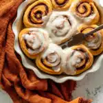 Frosted pumpkin cinnamon rolls on a serving platter