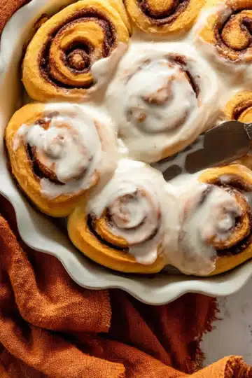 Frosted pumpkin cinnamon rolls on a serving platter