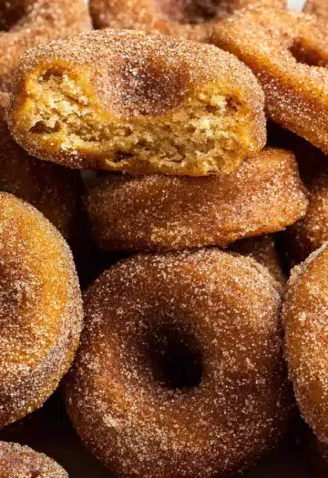 Pile of cinnamon sugar donuts with one broken apart