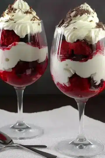 Boozy red velvet trifle desserts layered with cream and topped with chocolate shavings in wine glasses